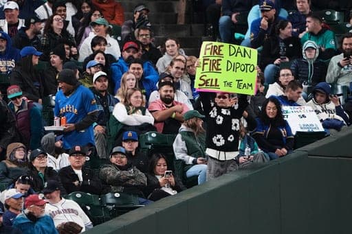 A Seattle Mariners fan holds a sign calling to sell the team and fire manager Dan Wilson and president of baseball operations Jerry Dipoto during a baseball game between the Mariners and the Los Angeles Angels, Friday, Sept. 25, 2026, in Seattle. (AP Photo/Lindsey Wasson) (AP Photo/Lindsey Wasson)