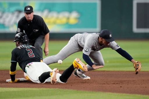 Arizona Diamondbacks' Geraldo Perdomo (2) slides safely into second base as New York Yankees shortstop George Lombard Jr., right, is unable to make the catch on the ball as umpire Cory Blaser looks on during the ninth inning of a baseball game, Friday, Sept. 18, 2026, in Phoenix. (AP Photo/Ross D. Franklin) (AP Photo/Ross D. Franklin)