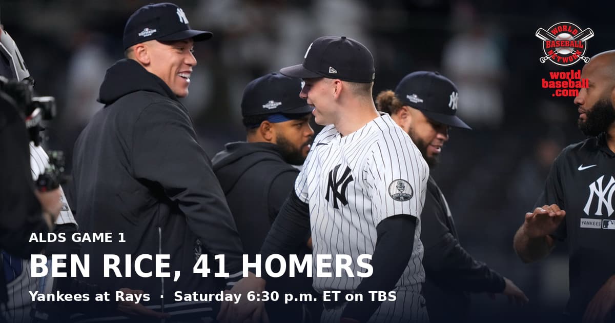 Aaron Judge, in a team jacket rather than a uniform, smiles with Ben Rice in pinstripes as the Yankees celebrate beating Boston in the Wild Card Series.