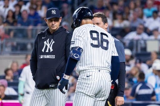New York Yankees manager Aaron Boone, left, attends to George Lombard Jr. (96) after Lombard suffered an injury while at-bat in the second inning during the second baseball game of a doubleheader against the Boston Red Sox, Saturday, Aug. 29, 2026, in New York. (AP Photo/Corey Sipkin) (AP Photo/Corey Sipkin)
