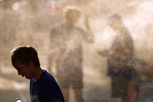 Fans cool off in a mister as temperatures approach 100 degrees before a baseball game between the Kansas City Royals and the Arizona Diamondbacks, Tuesday, Sept. 8, 2026, in Kansas City, Mo. (AP Photo/Charlie Riedel) (AP Photo/Charlie Riedel)