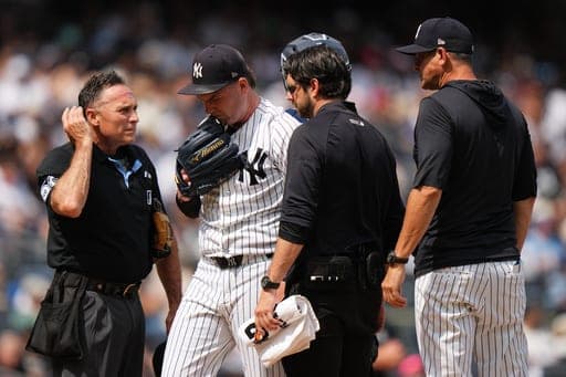 New York Yankees manager Aaron Boone, right, and home plate umpire Dan Iassogna, left, watch as pitcher Ryan Weathers leaves during the fourth inning of a baseball game against the Toronto Blue Jays Saturday, Aug. 22, 2026, in New York. (AP Photo/Frank Franklin II) (AP Photo/Frank Franklin II)