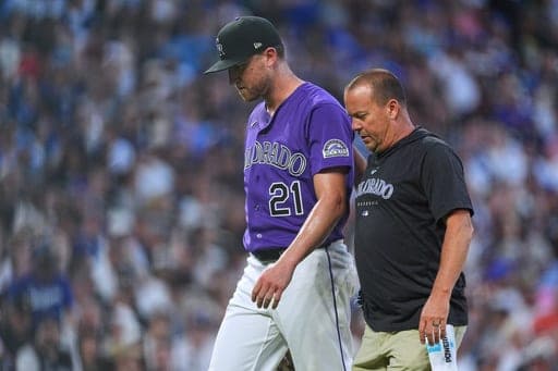 Colorado Rockies starting pitcher Kyle Freeland, back, is escorted to the clubhouse by trainer Heath Townsend after Freeland was pulled from the mound because of injury in the fourth inning of a baseball game against the Los Angeles Dodgers Wednesday, Aug. 19, 2026, in Denver. (AP Photo/David Zalubowski) (AP Photo/David Zalubowski)