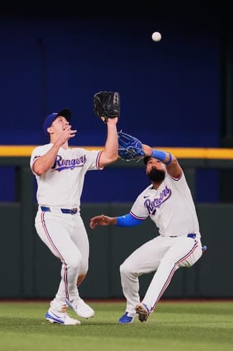 Texas Rangers left fielder Wyatt Langford, left, and center fielder Ezequiel Duran attempt to catch a fly out by New York Mets' Marcus Semien during the seventh inning of a baseball game Thursday, Sept. 24, 2026, in Arlington, Texas. (AP Photo/Julio Cortez) (AP Photo/Julio Cortez)