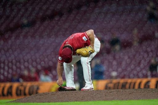 Cincinnati Reds pitcher Emilio Pagán pauses to scrape the bottom of his cleat as he pitches in the rain during the ninth inning of a baseball game against the St. Louis Cardinals, Wednesday, Aug. 19, 2026, in Cincinnati. (AP Photo/Carolyn Kaster) (AP Photo/Carolyn Kaster)