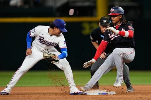 Washington Nationals' CJ Abrams, reaches second for a double ahead of the attempted tag by Texas Rangers' Nicky Lopez as umpire Brian Walsh (60) looks on in the ninth inning of a baseball game Wednesday, Aug. 19, 2026, in Arlington, Texas. (AP Photo/Tony Gutierrez) (AP Photo/Tony Gutierrez)